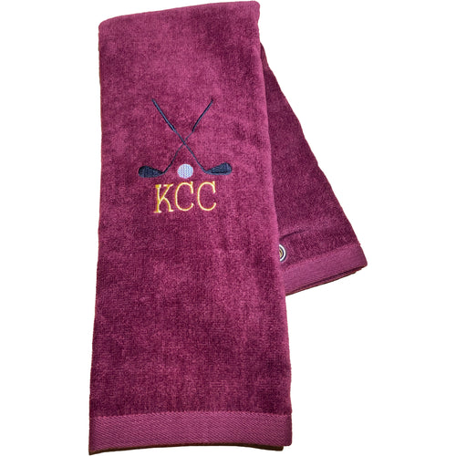 Burgundy golf towel with two golf clubs and a golf ball. Below the golf clubs are the letters KCC. These are personalized with your favorite golfer's initials.