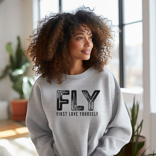 Women wearing gray crewneck sweatshirt that reads First Love Yourself