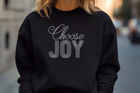 Woman wearing a black crewneck sweatshirt that reads Choose Joy in crystal rhinestones